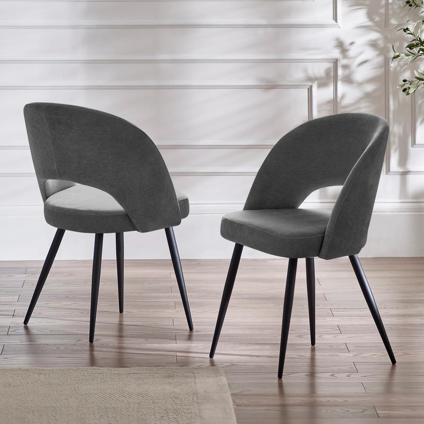 Two gray chairs with black legs on a wooden floor.