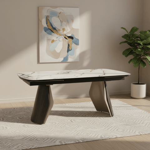 Modern dining table with marble top and wooden legs in a room with abstract art and plant.