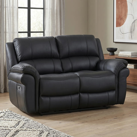 Black leather reclining 2 Seater sofa in a modern living room setting with wood floors, a sideboard, and a window in the background.