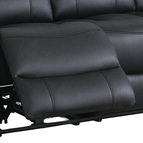 Close-up of a black leather reclining sofa seat with the footrest extended, showing padded segmented cushions and stitching details.