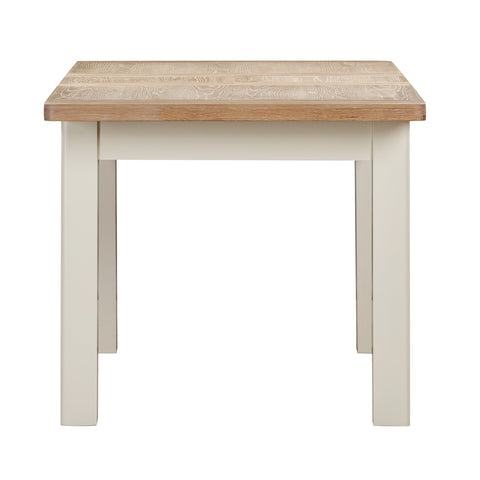 Close up of a Foxington Dining Table, with a light wood top and painted off-white legs and frame.  Shown on a white background.