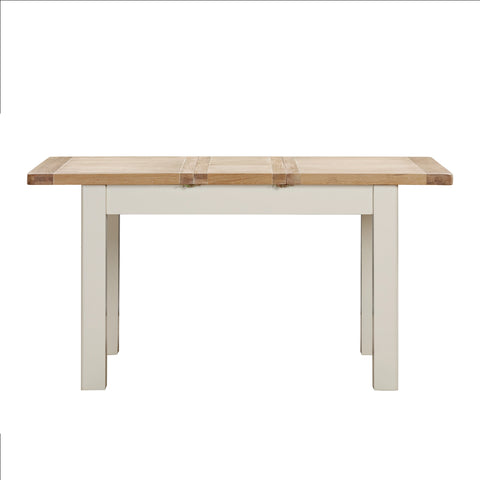 A close up of a Foxington Dining Table extended, with a light natural wood top and off-white coloured frame, shown against a plain white background.