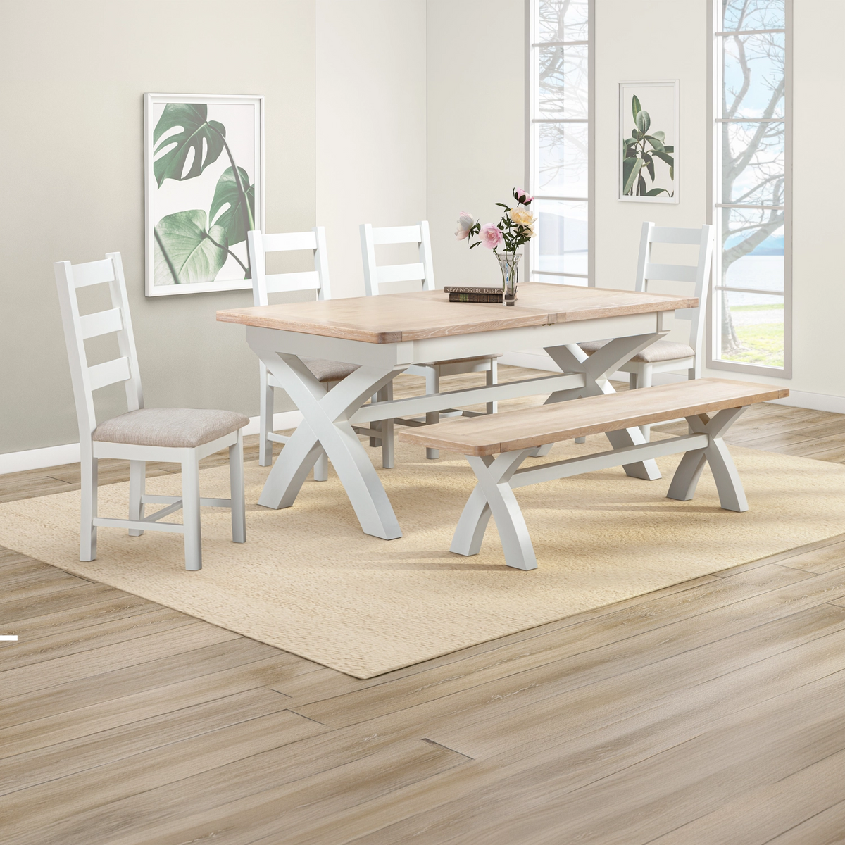 Lifestyle image of a Foxington Painted Dining Set, including a rectangular table, two chairs, and a bench, shown in a bright, modern dining room setting with a beige rug and wood flooring.