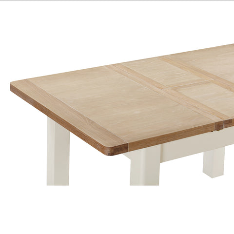 Close-up of the Foxington Dining Table extended. The table is a light natural wood top.  The frame and legs are painted an off-white colour.  Shown on a white backgroun