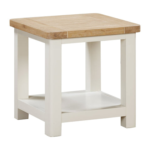 A close up image of Foxington Lamp Table with a light natural wood top and an off-white painted frame, featuring a lower shelf , shown on a solid white background.