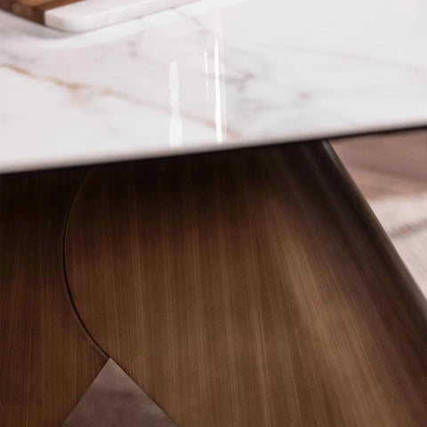 Close-up of a modern dining table featuring a glossy white marble top with subtle gold veining and a sculptural, curved dark brown wooden base.