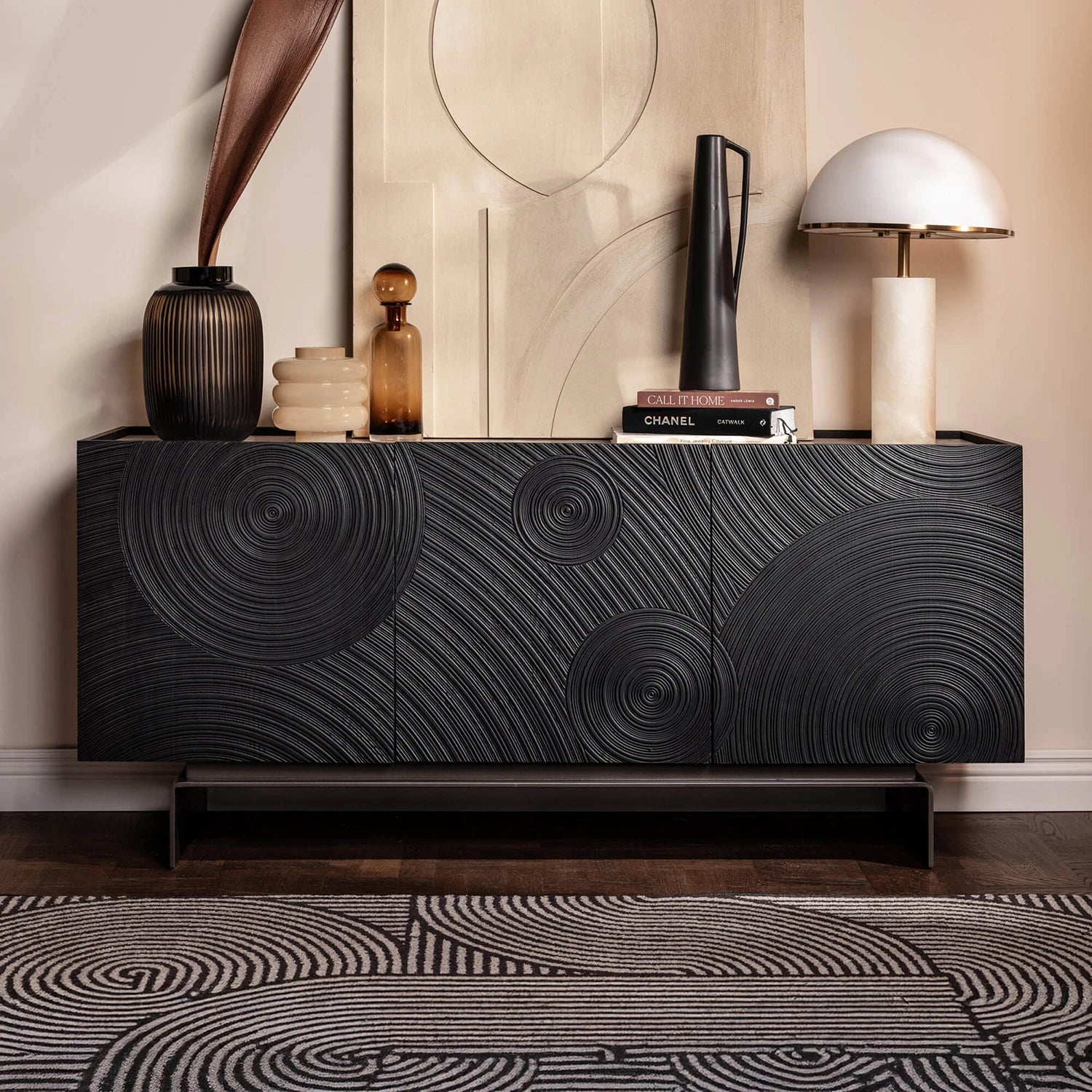 Black textured sideboard with decorative items against a beige wall.