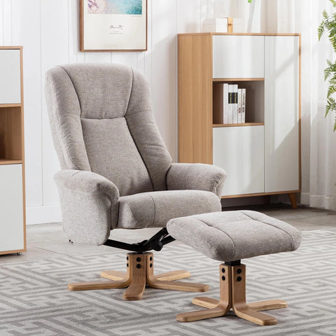 A taupe Hawaii Bigelow upholstered recliner chair with a matching ottoman, both on wooden swivel bases, shown in a bright modern room with white paneled walls and a wood-and-white cabinet.