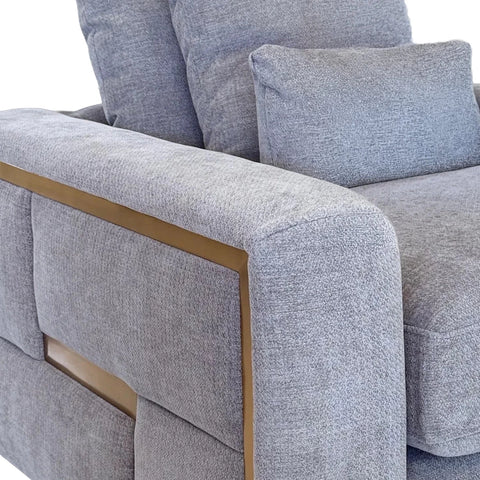 Close-up of a light gray textured fabric sofa with a gold metal trim accent along the armrest.