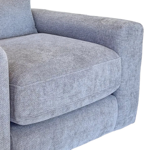 Close-up of a light gray textured fabric armchair showing the seat cushion, armrest, and side bolster against a white background.