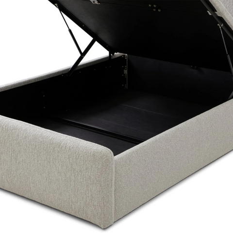 A light beige upholstered storage bed with the top cushion lifted open to show the black-lined storage compartment, photographed on a white background.