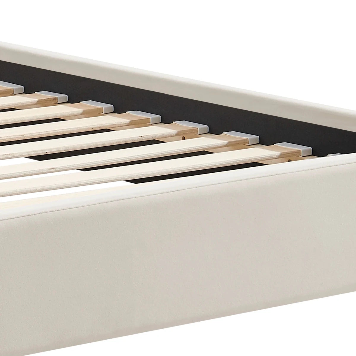 Close-up of a bed frame corner showing a light beige velvet upholstered foot end and natural wood slats.