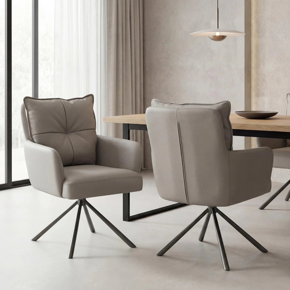 Two modern upholstered dining chairs with tufted back cushions and dark metal swivel legs, shown in a bright contemporary dining room beside a wooden table.