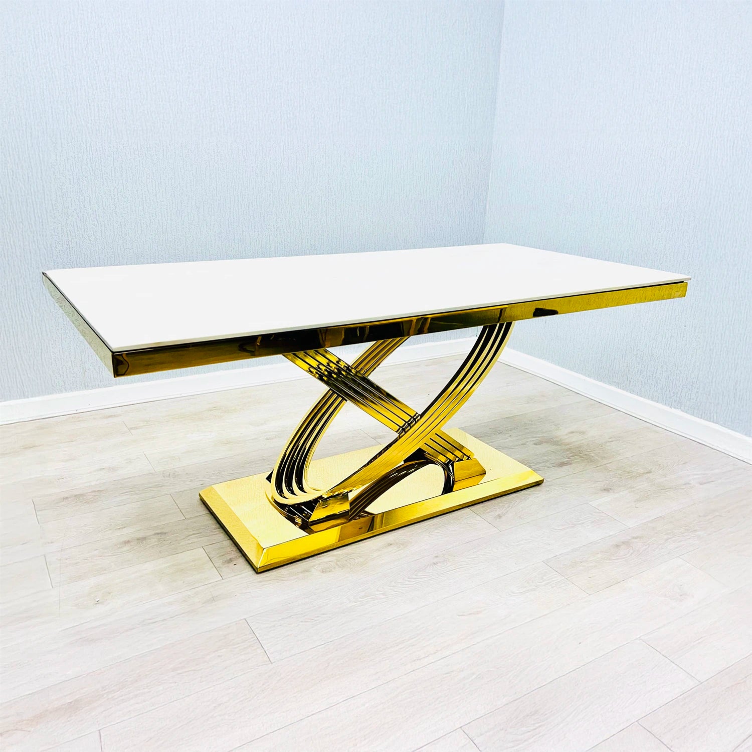 Modern dining table with gold base and Cream Marble top on a light wooden floor.