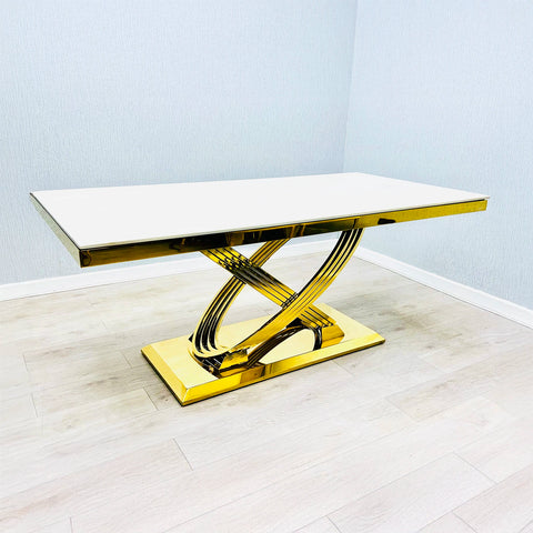 Modern dining table with gold base and Cream Marble top on a light wooden floor.