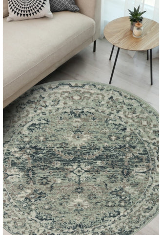 Round sage green rug with traditional inspired pattern.