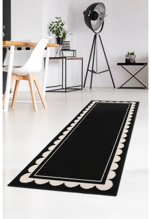 Black runner rug with bold scallop pattern design.