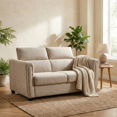 Beige sofa bed in a living room with plants and a lamp