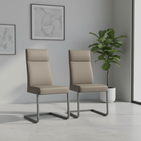 Two modern high-back dining chairs in beige faux leather with curved gray metal cantilever legs, shown in a minimalist room setting with a potted plant and framed wall art.