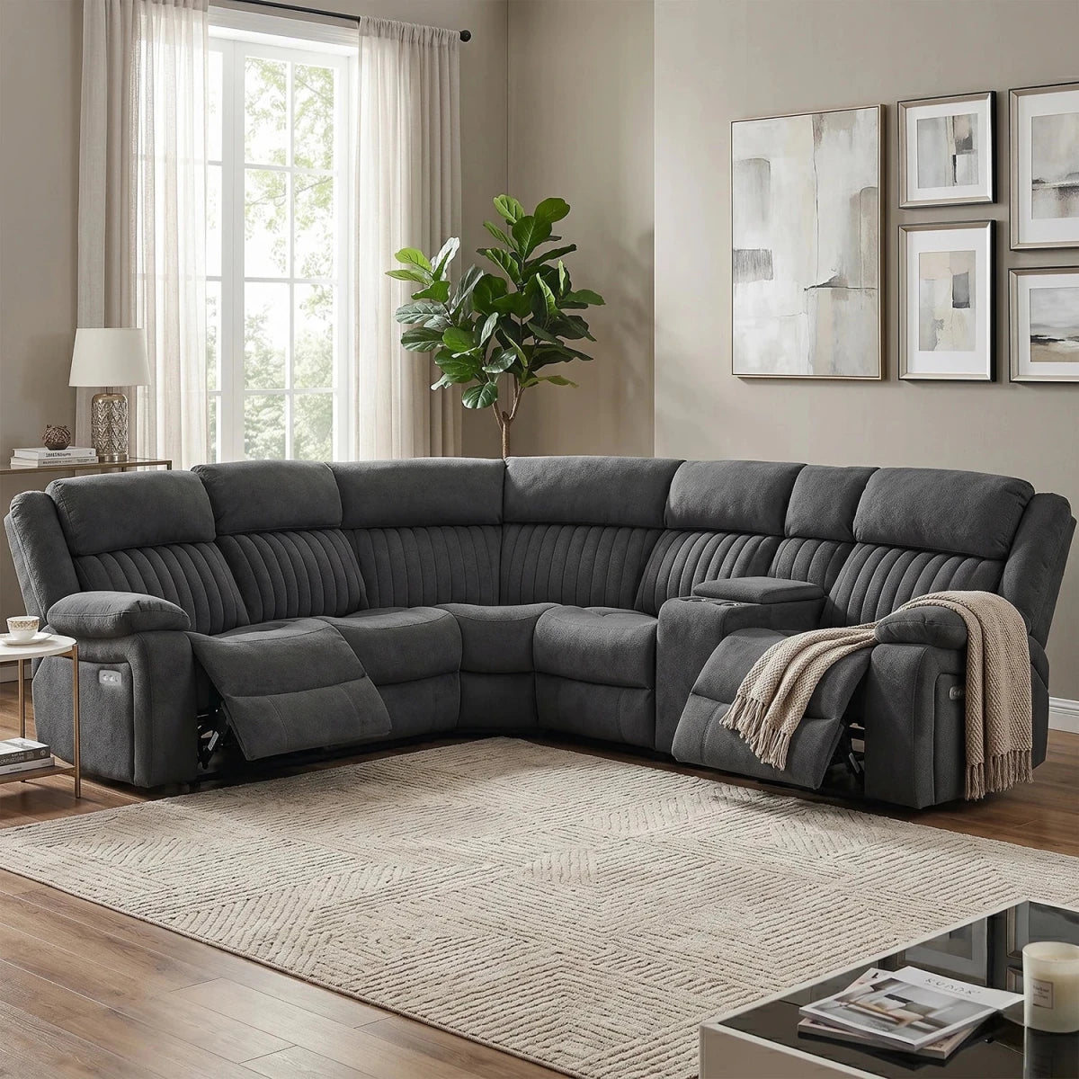 A dark gray U-shaped sectional sofa with reclining seats, shown in a styled living room with a beige rug, window, plant, and wall art.