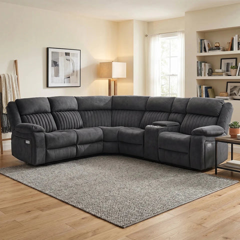 A dark gray modular reclining sectional sofa with built-in cup holders, shown in a staged living room setting with a patterned area rug, wood floors, and a bookshelf in the background.