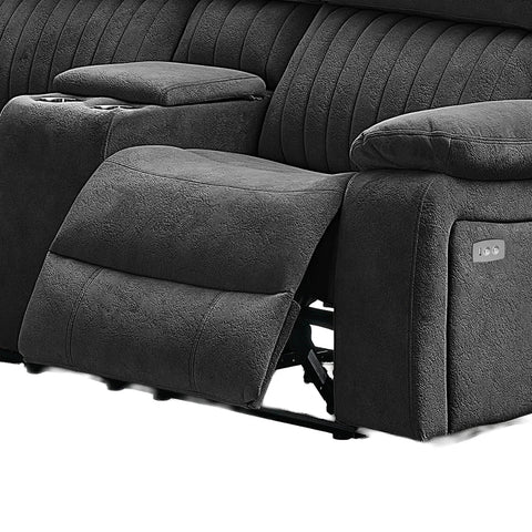 Close-up of a dark gray reclining sofa with the footrest extended, showing padded armrests, channel-tufted back cushions, and a side control panel.
