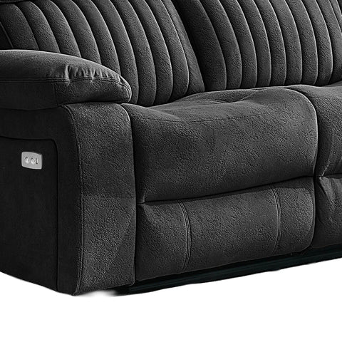 Close-up of a dark gray upholstered reclining sofa showing the padded armrest, ribbed back cushions, seat area, and a small control panel on the side.