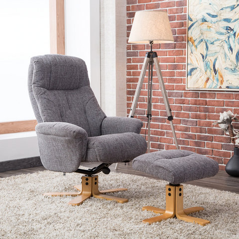 Gray fabric Muscat recliner chair with matching ottoman in a styled room setting featuring a brick wall, tripod floor lamp, and abstract wall art.