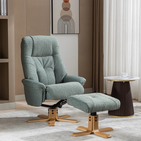 A modern Muscat upholstered recliner chair with a matching ottoman in a light sage green teal fabric, set in a contemporary living room with a wooden floor, beige walls, and a round side table.