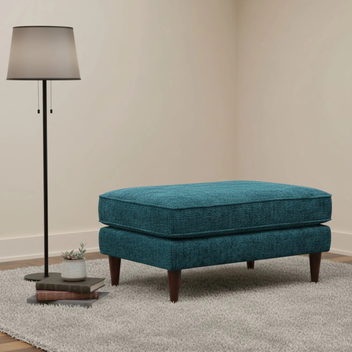 Compact footstool with neutral upholstery and wooden legs.