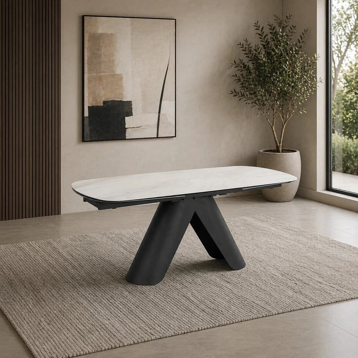 Modern dining table with black legs and white top in a room with a painting and plant.