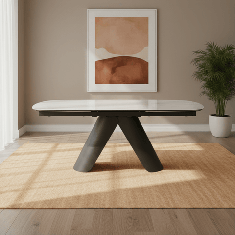 Modern dining table with black legs in a room with a painting and plant on the wall.