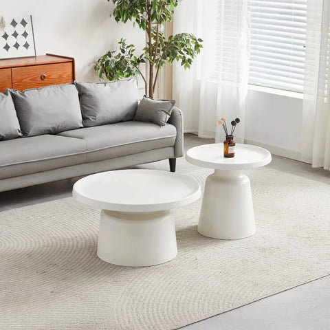 Modern living room with a gray sofa, white coffee tables, and decorative elements.