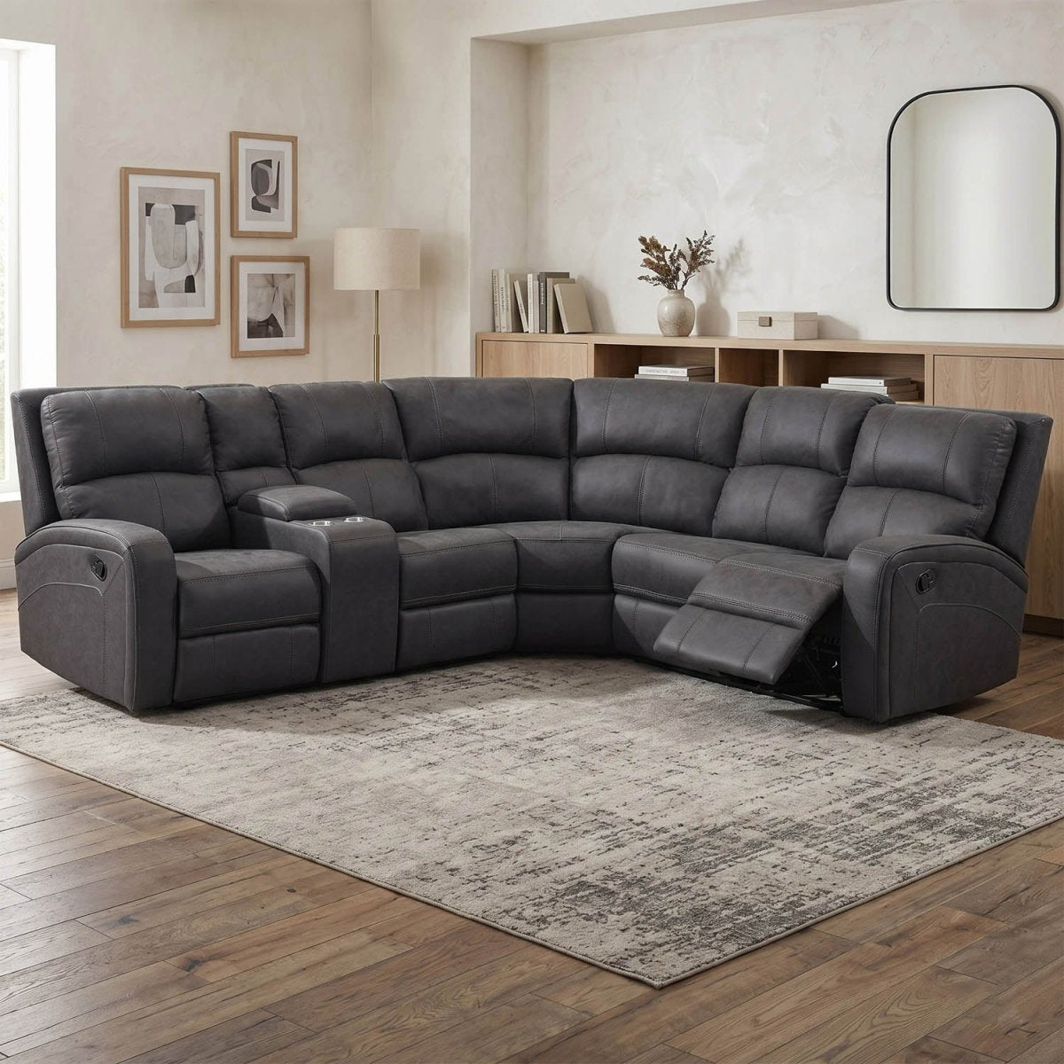 A dark gray upholstered sectional sofa with two reclining seats, shown in a staged living room with wood flooring, a patterned rug, wall art, and a cabinet.