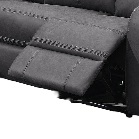 Close-up of a dark gray reclining sofa showing the extended footrest and padded armrest with contrast stitching.