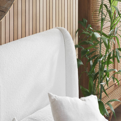 Wide upholstered headboard with rounded edges and textured fabric.