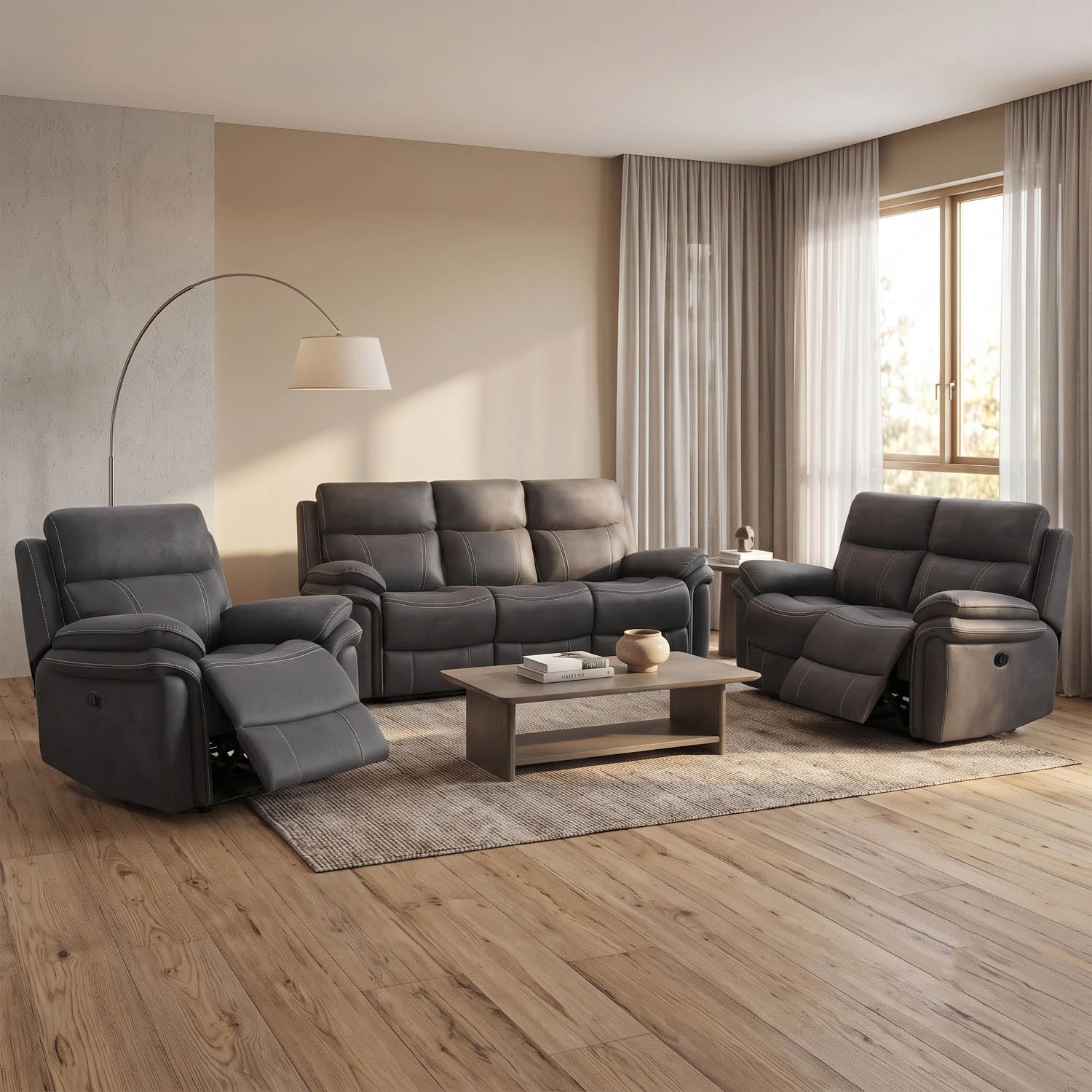 A dark gray three-piece reclining living room furniture set, including a loveseat, a recliner, and a sofa, arranged in a modern living room with a coffee table, rug, and a floor lamp.
