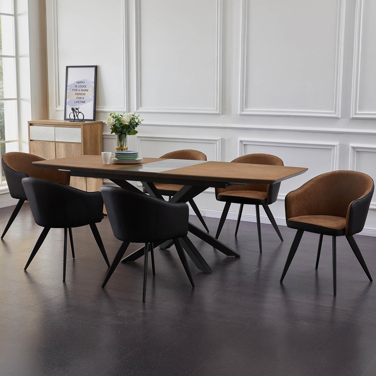 A modern dining room set featuring a rectangular wooden table with a black metal star base and six upholstered chairs, including two black chairs with brown seats, two black chairs with brown backs, and one black chair with a solid brown back, set in a bright room with white paneled walls.