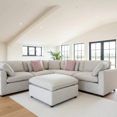 Large grey corner sofa set with footstool and feather cushions.