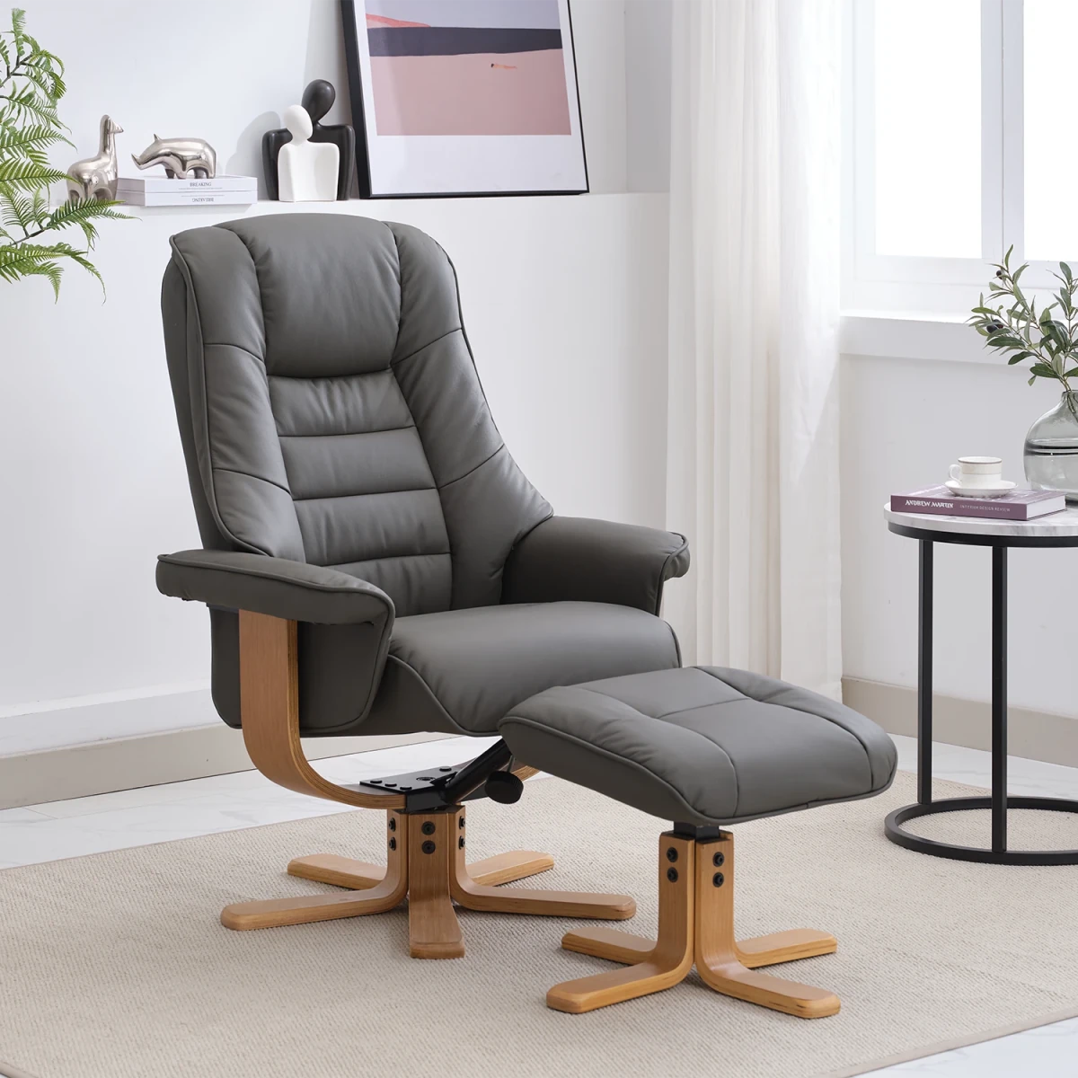 A modern gray leather recliner chair with a matching ottoman, both on wooden swivel bases, shown in a bright, contemporary living room setting.