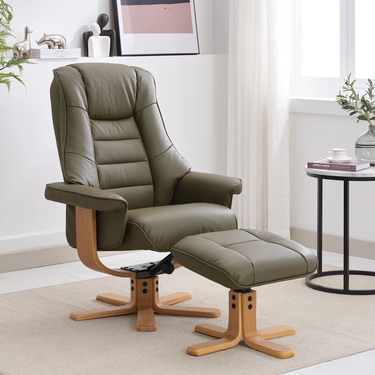 An olive green leather recliner chair with a matching ottoman, both with light wood bases, shown in a bright, modern living room setting.
