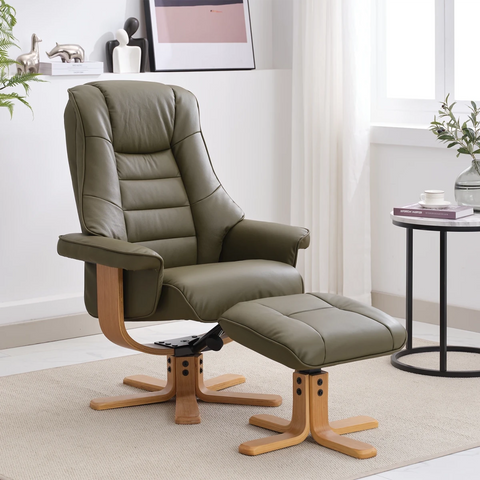 An olive green leather recliner chair with a matching ottoman, both with light wood bases, shown in a bright, modern living room setting.