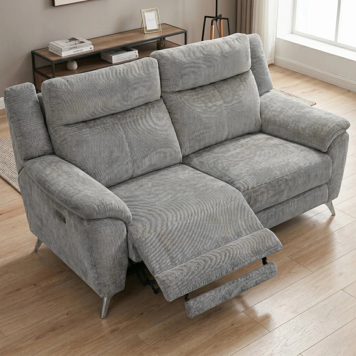 A light gray reclining sofa with a textured fabric, shown in a living room setting with its footrest extended, on a light wood floor.