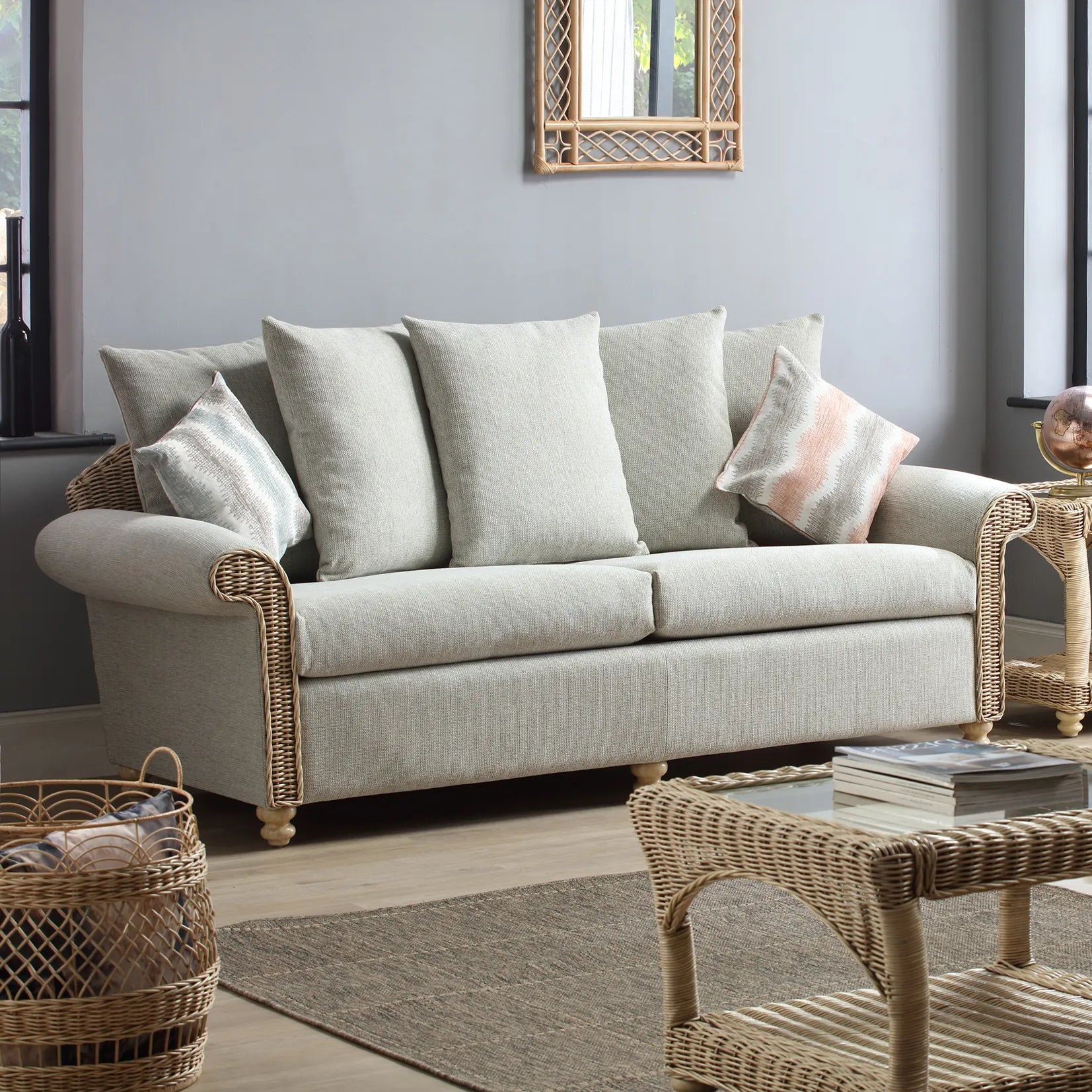 Desser Samford Rattan 3 Seater Sofa with Scatter Cushions in Pebble Fabric. Also available in 2 Seater, Swivel Chair, Swivel Rocker, Armchair and Footstool. Style with matching Coffee Table and Lamp Table. Choose from a variety of fabrics - 3 seater sofa in Lifestyle image