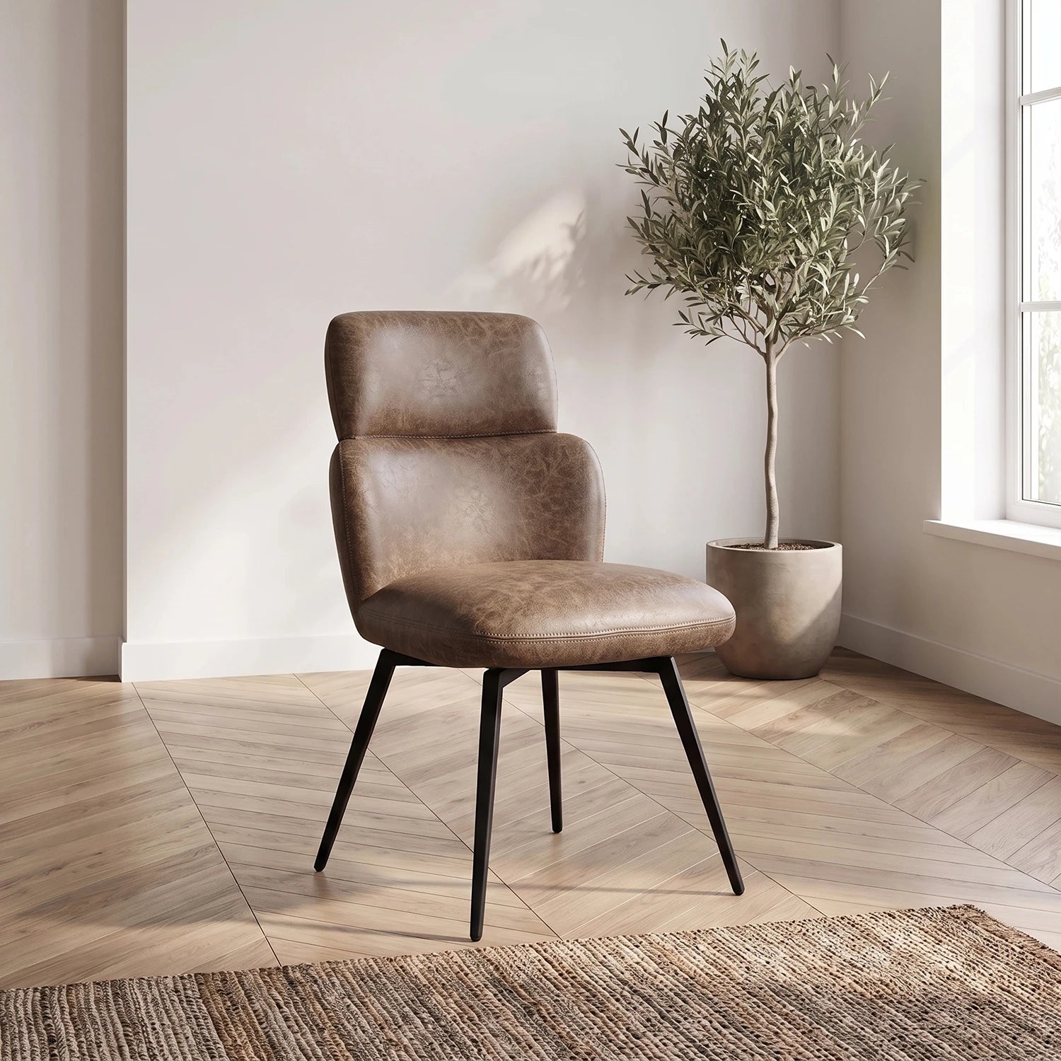A tan vintage pu leather upholstered Dining chair with black metal legs, styled in a bright room next to a potted olive tree.