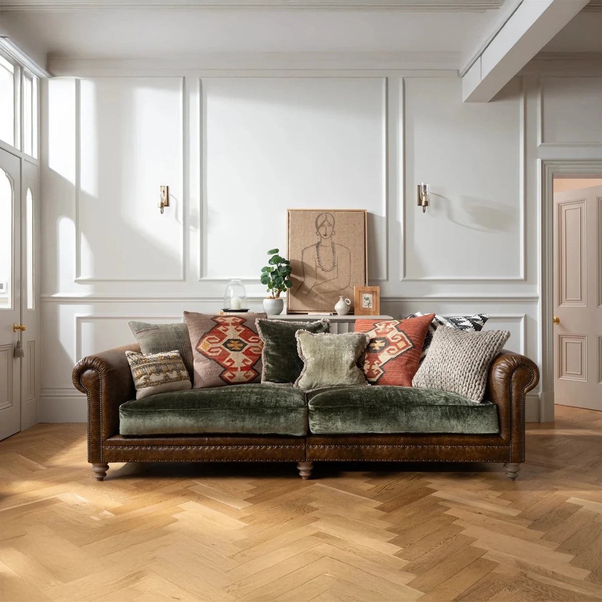 Green velvet Constable sofa by Tetrad with patterned cushions in a room with white walls and wooden flooring.