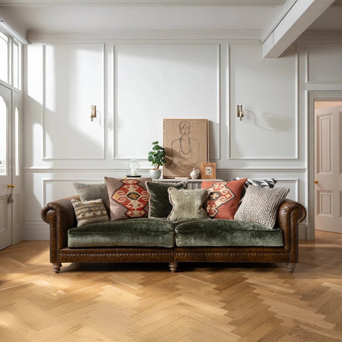 Green velvet Constable sofa by Tetrad with patterned cushions in a room with white walls and wooden flooring.