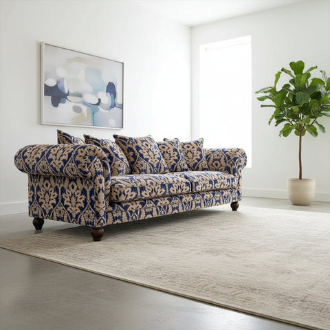 Decorative sofa with blue and beige pattern in a room with wooden flooring and white walls.