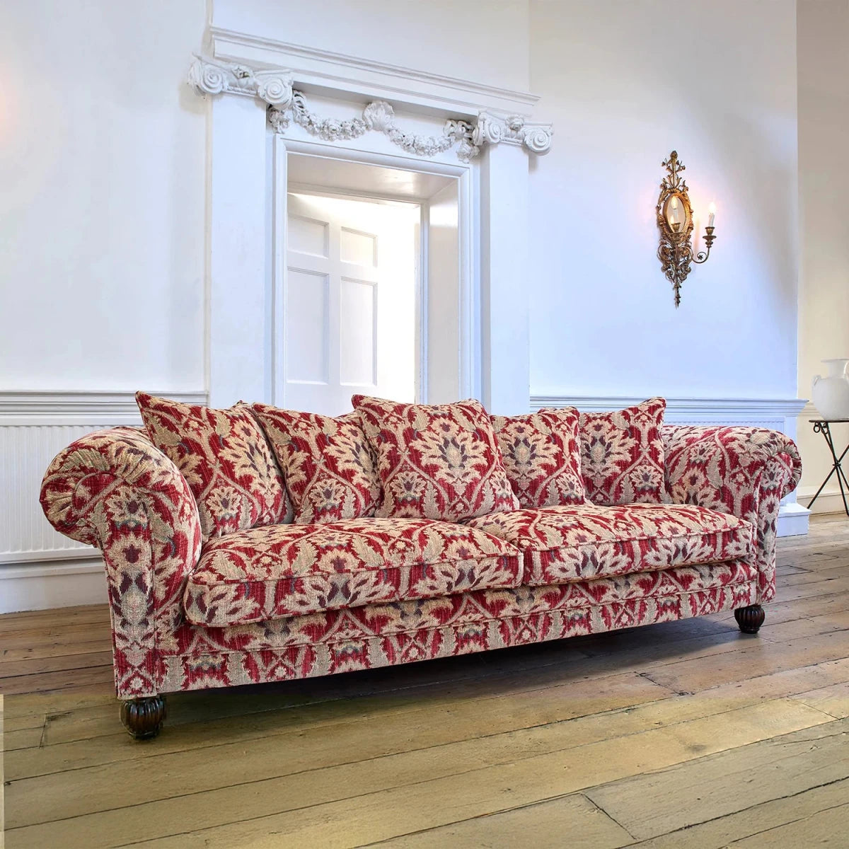 Red and beige patterned elgar sofa in a room with wooden flooring and white walls