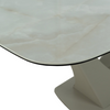 Close-up of a modern dining table showing a curved white marble-look top with a thin black edge and a sculptural white pedestal base against a white background.